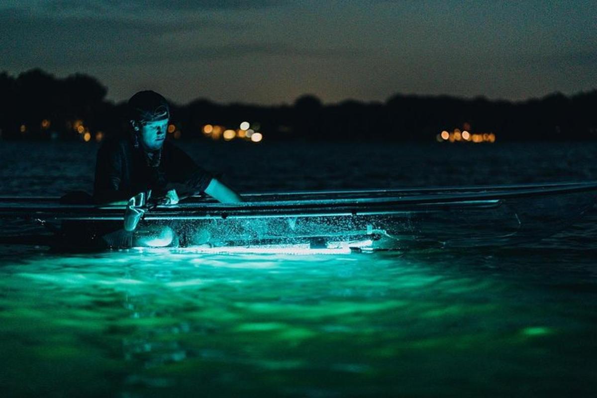 Un hombre sentado en un bote en el agua por la noche.
