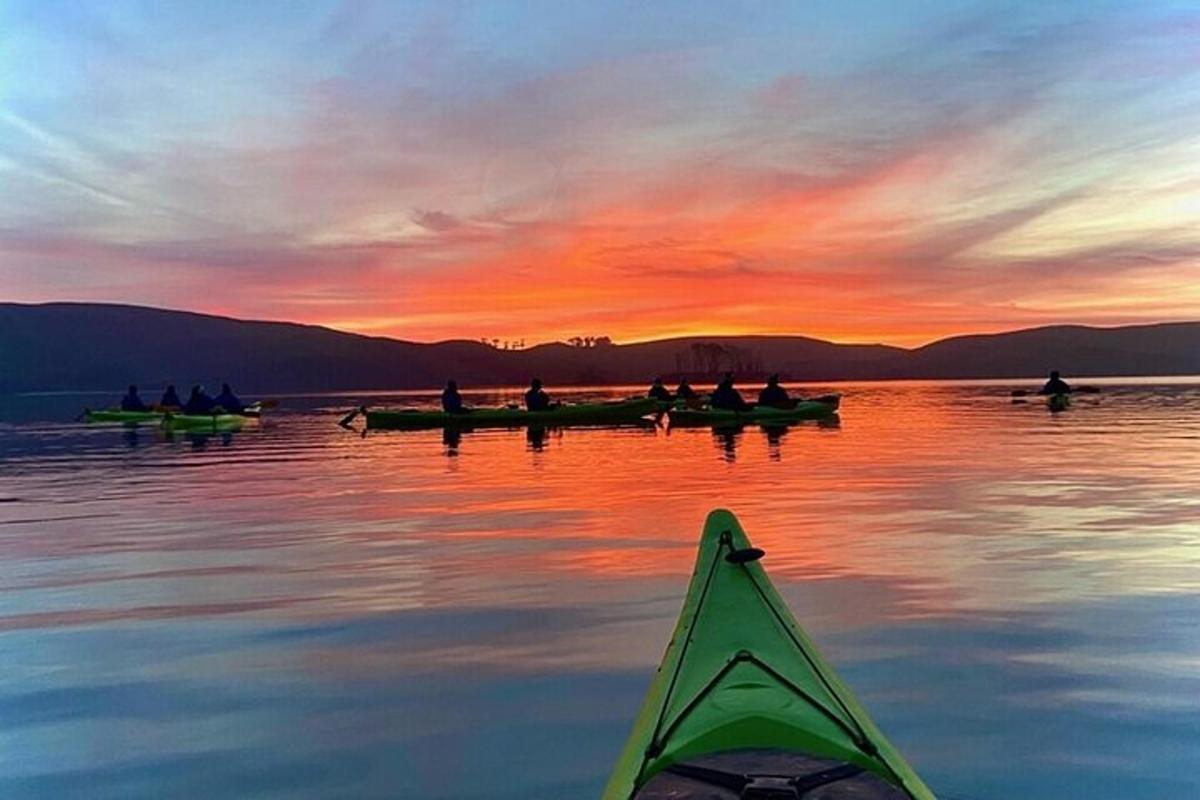 ryhmä ihmisiä veneissä järvellä auringonlaskun aikaan