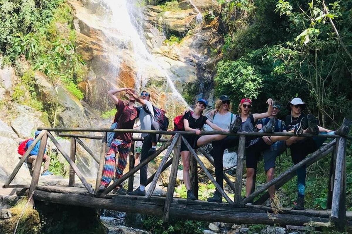 sekumpulan orang duduk di atas jambatan di hadapan air terjun