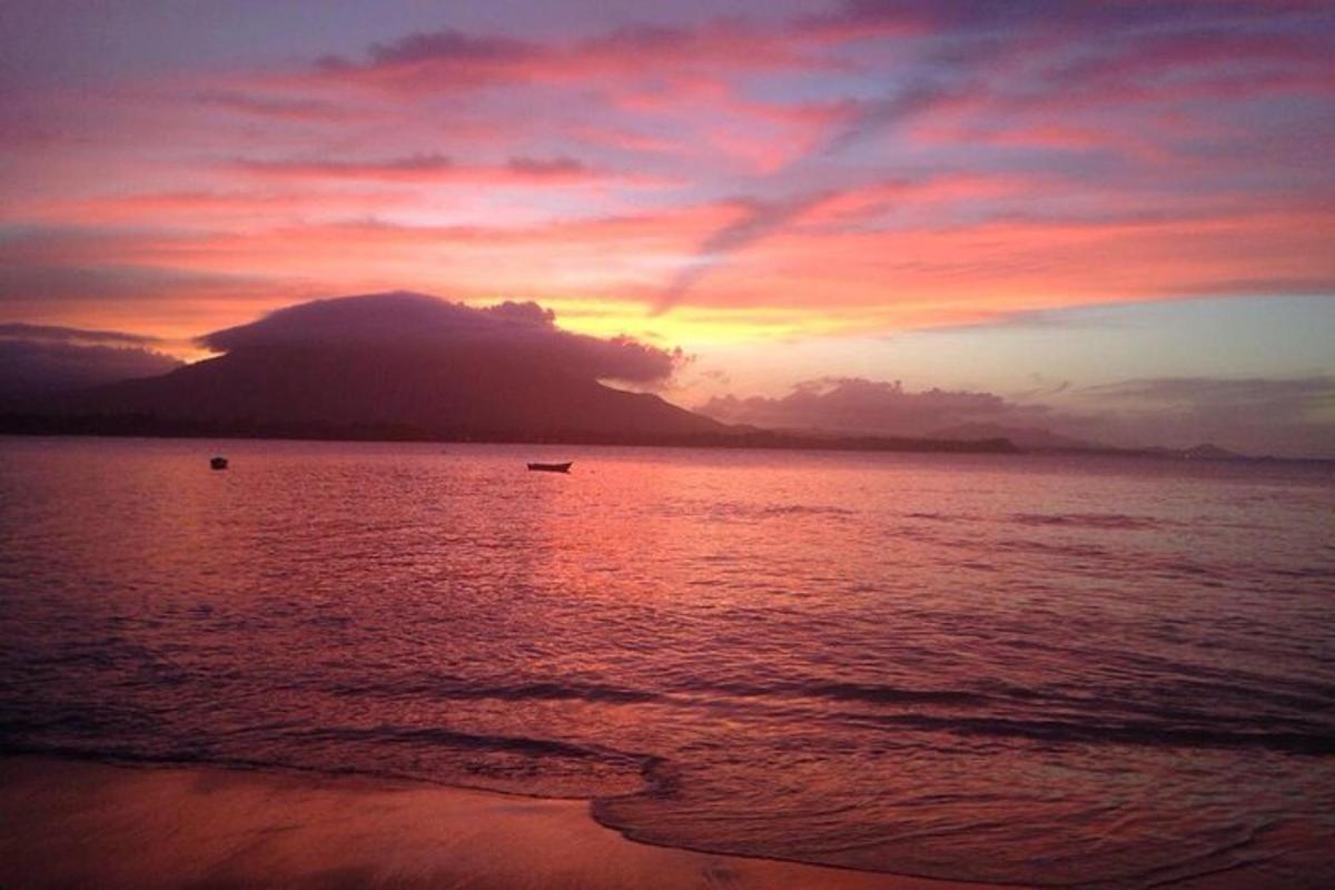 un tramonto sulla spiaggia con una barca in acqua
