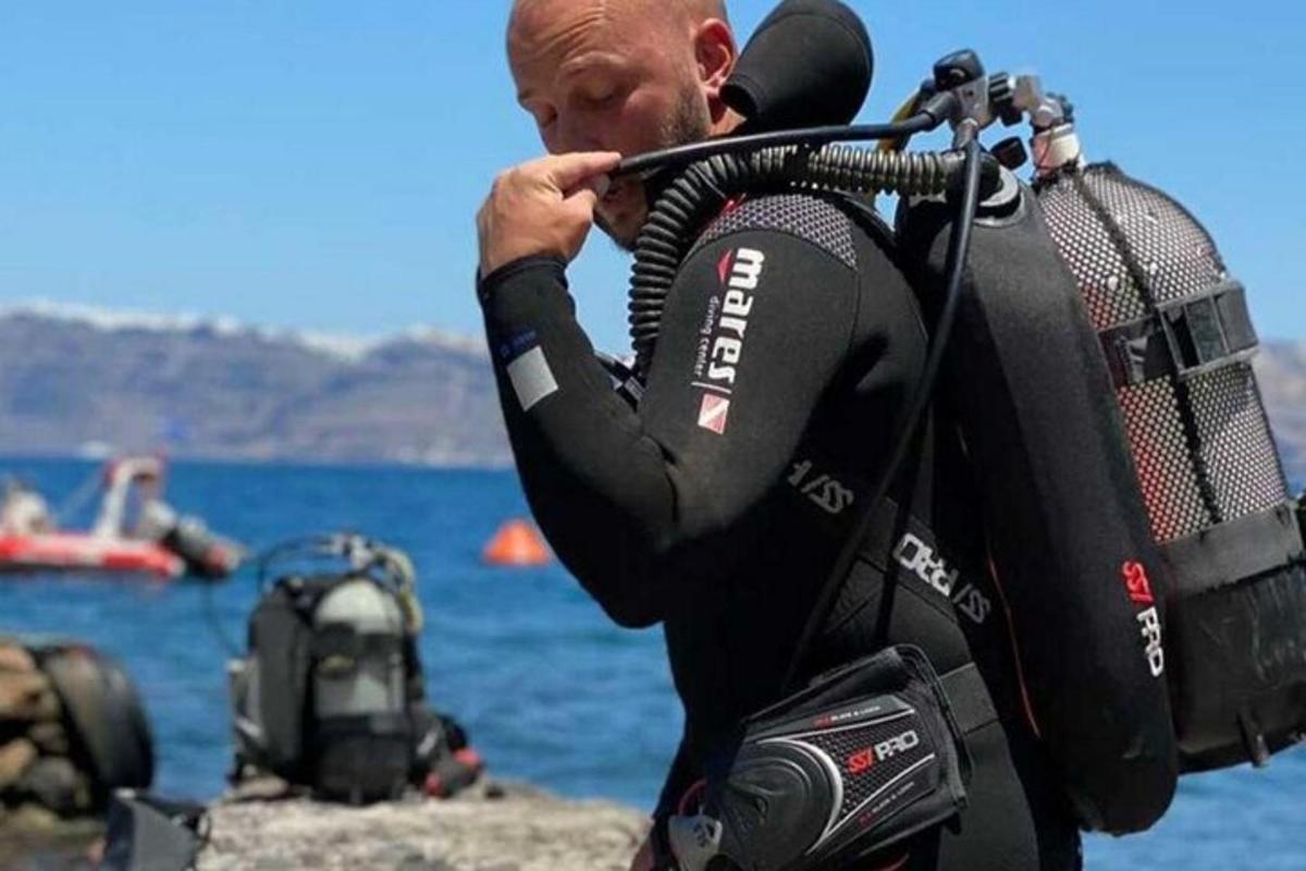 ένας άντρας με στολή κατάδυσης που κρατάει μια φωτογραφική μηχανή