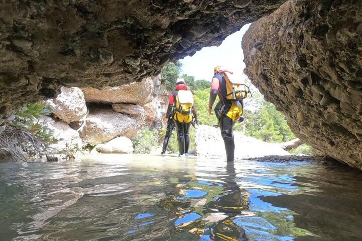 two people walking through the water in a cave