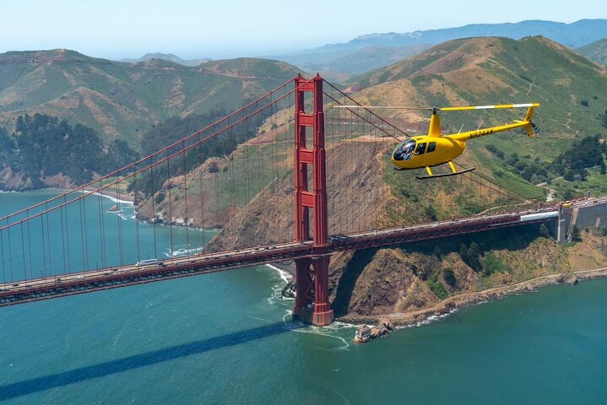 Žlutý vrtulník letící nad mostem Golden Gate