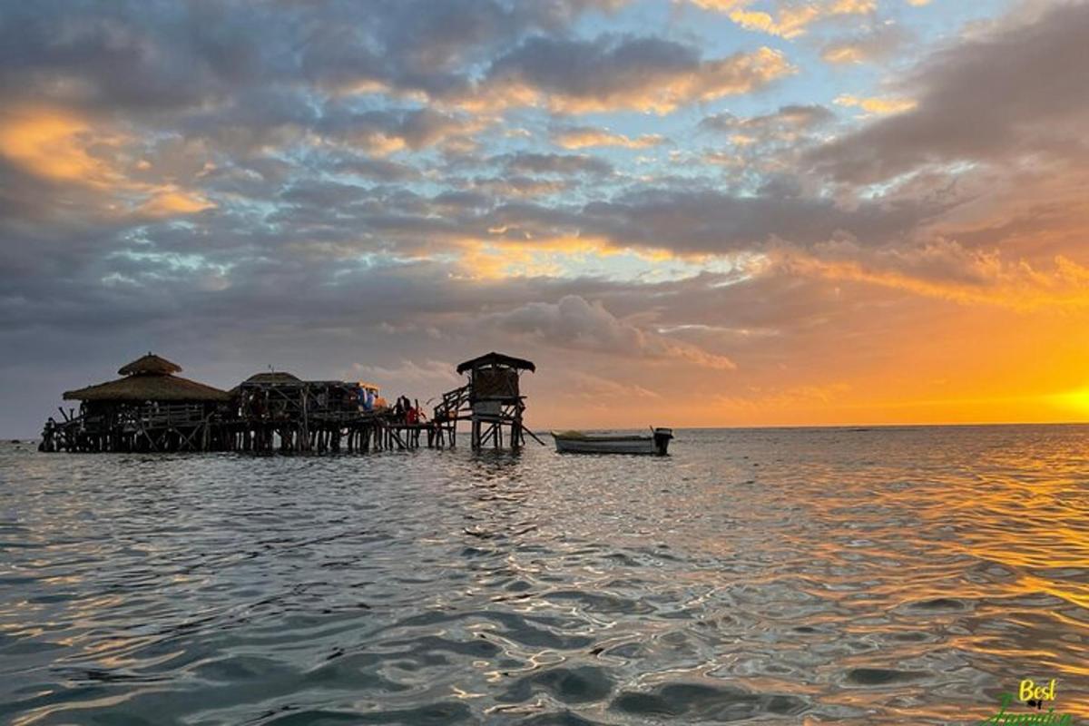 un moll a l'aigua amb un vaixell i una posta de sol