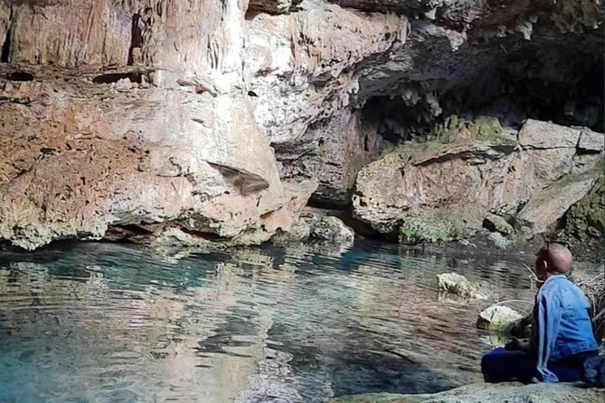 un uomo seduto su una roccia vicino a un fiume