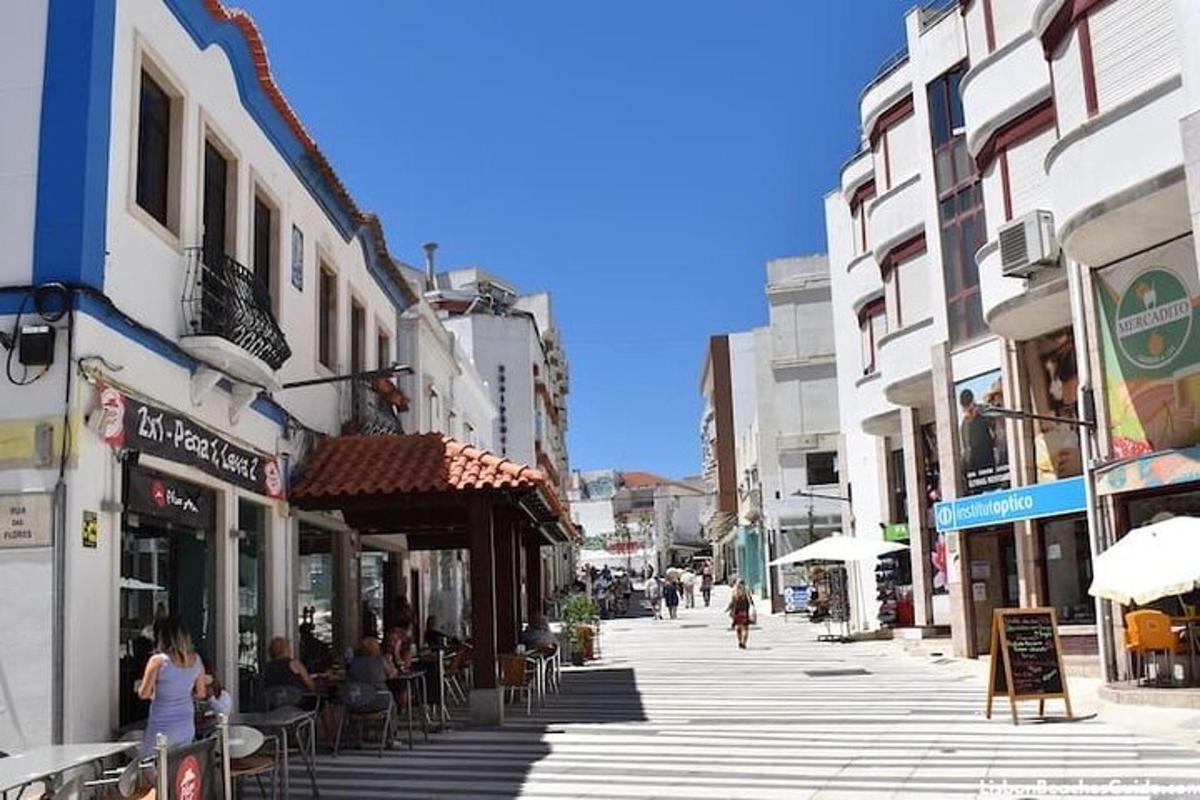 ένας δρόμος της πόλης με ανθρώπους να κάθονται σε τραπέζια στο πεζοδρόμιο