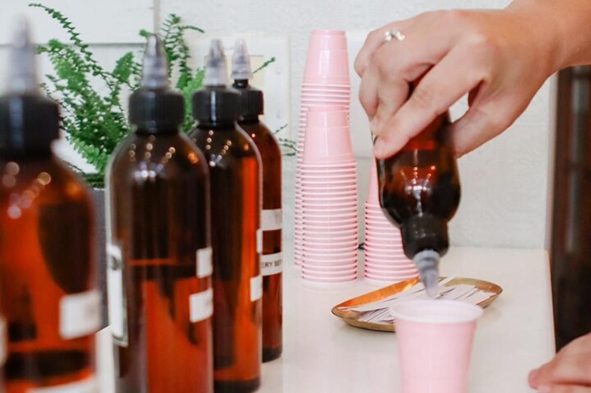 a person pouring a drink into a cup next to bottles