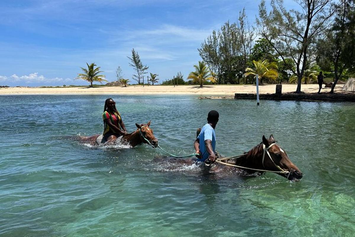 a couple of people riding horses in the water
