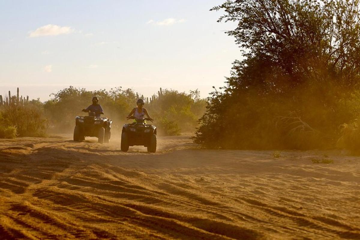 două persoane care călătoresc pe ATV-uri pe un drum de pământ