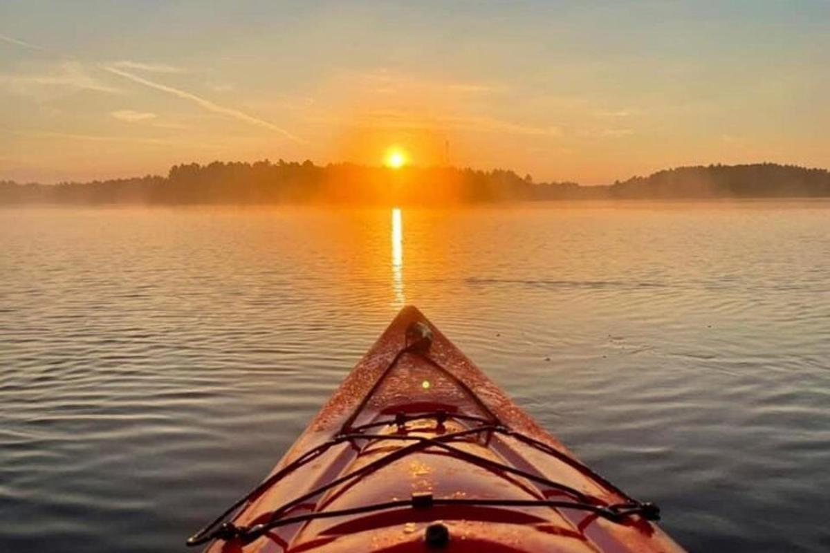 inimene kajakis järvel päikeseloojangul