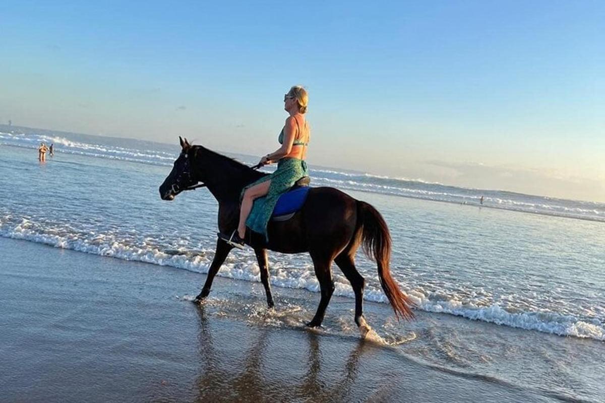 una noia jove muntant a cavall a la platja