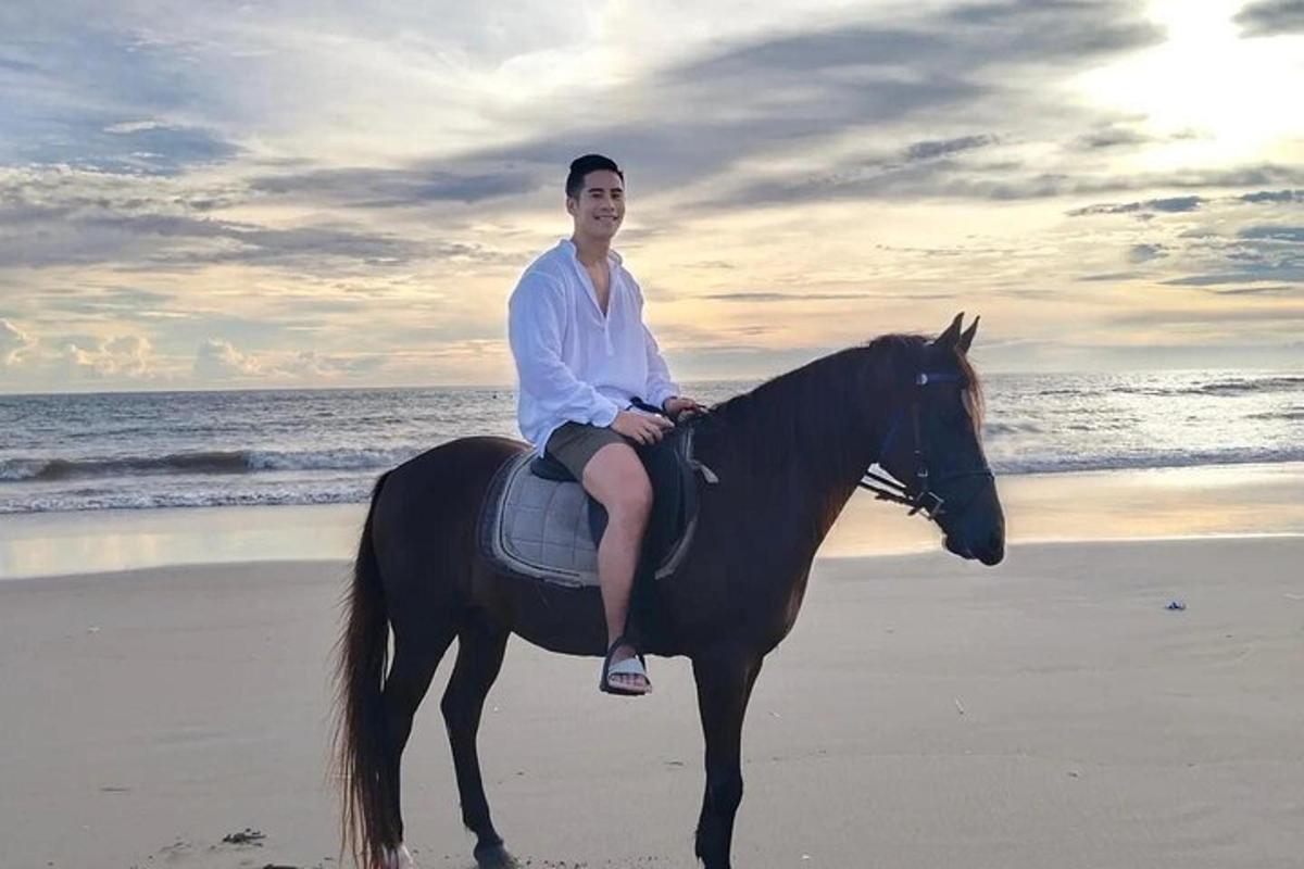 a man sitting on a horse on the beach