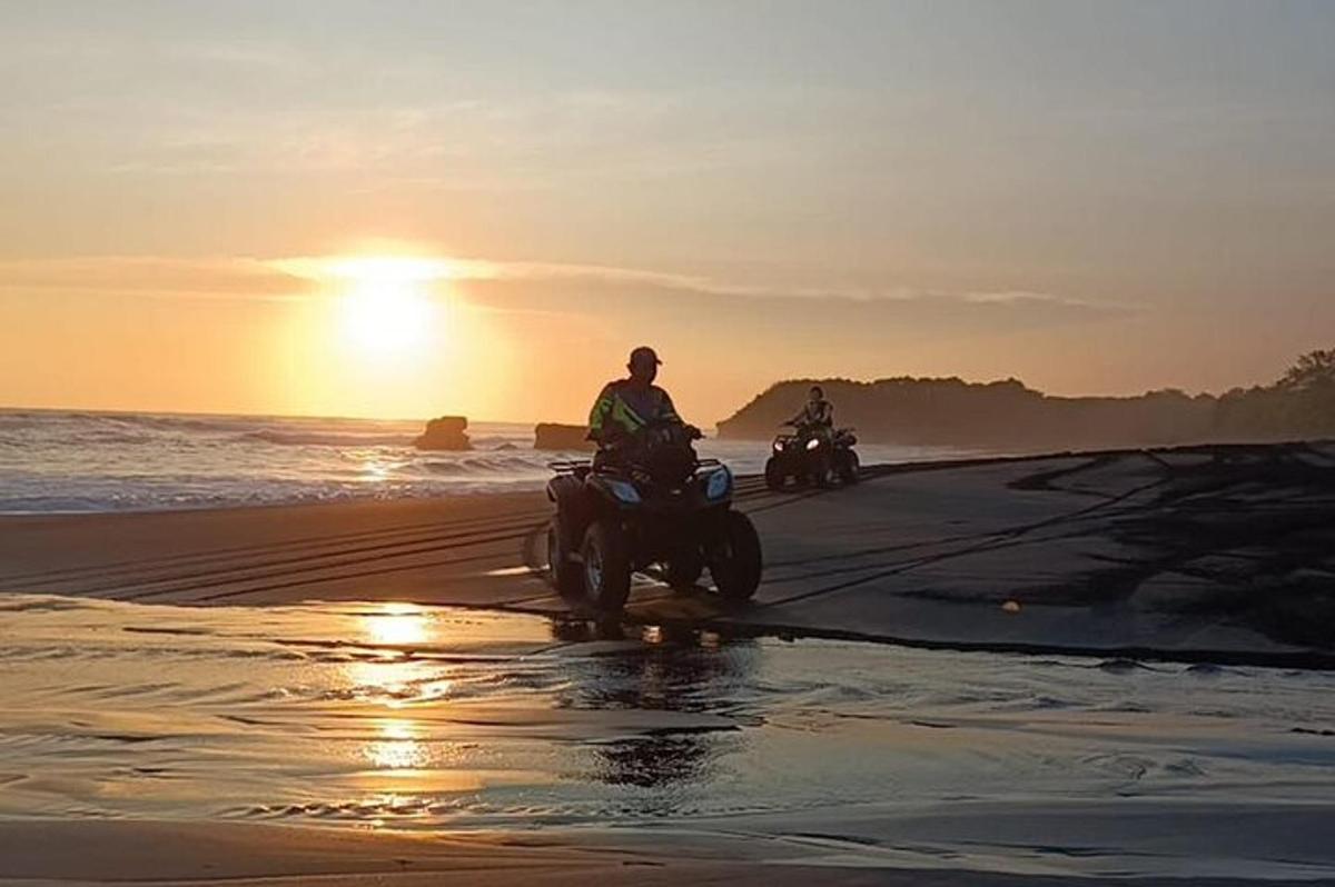 dva lidé jedoucí na motorkách na pláži při západu slunce