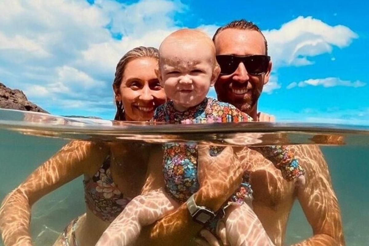 um homem e uma mulher segurando uma prancha de surfe na água