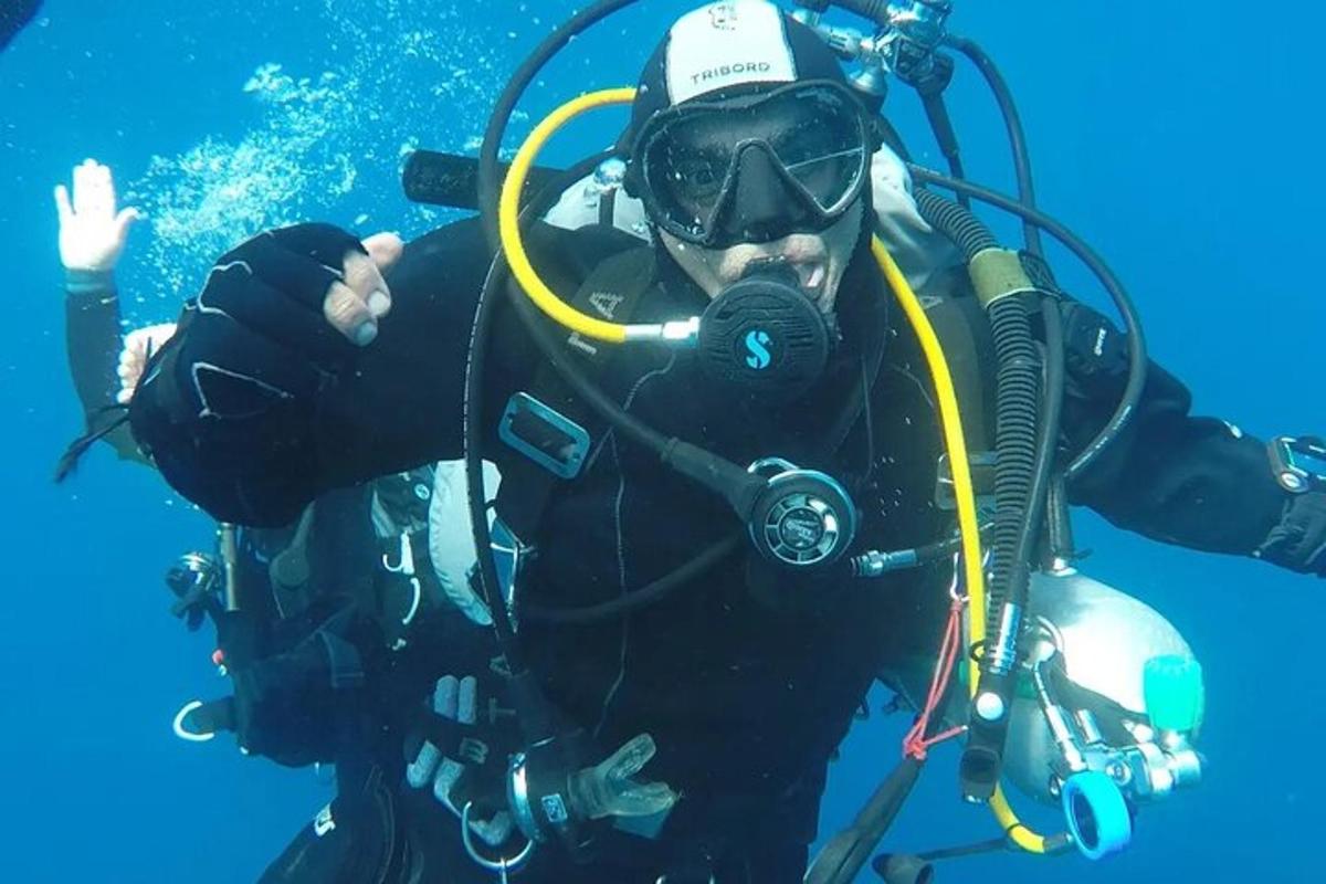 Moški v potapljaški obleki in očalih je pod vodo