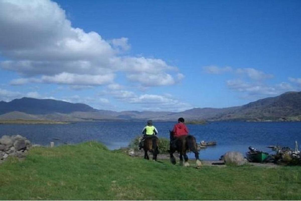 Dos personas montando a caballo junto a un cuerpo de agua