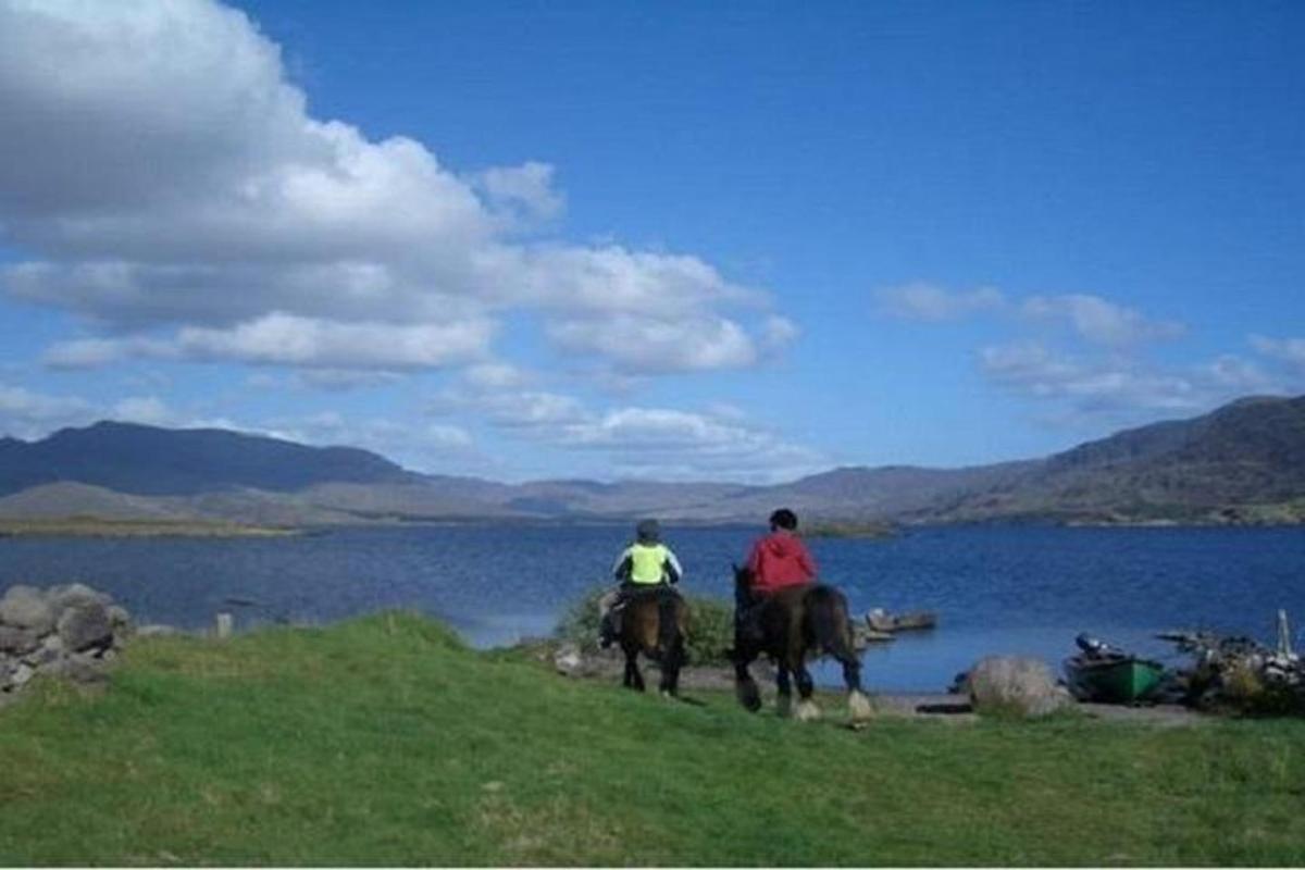 Dos personas montando a caballo junto a un cuerpo de agua