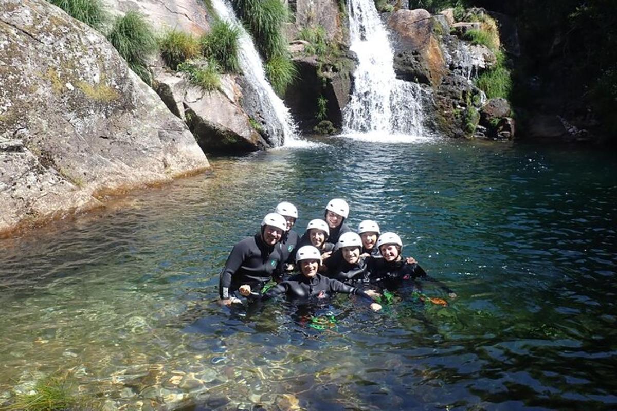 um grupo de pessoas na água em frente a uma cachoeira