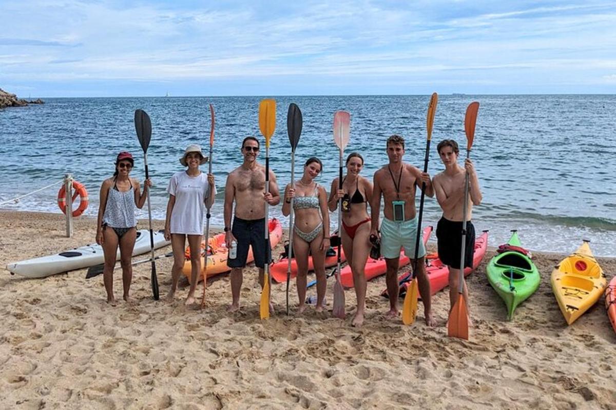 sekumpulan orang berdiri di pantai dengan kayak