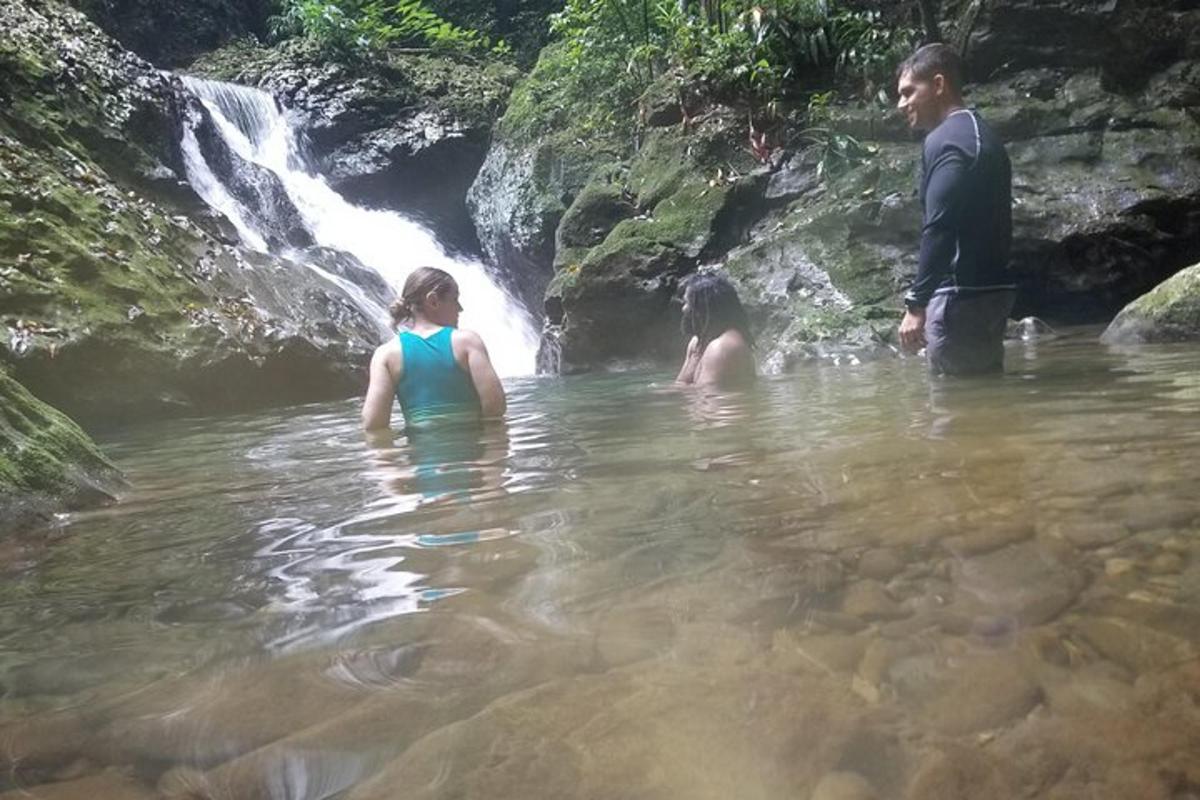 dva lidé stojící ve vodě poblíž vodopádu