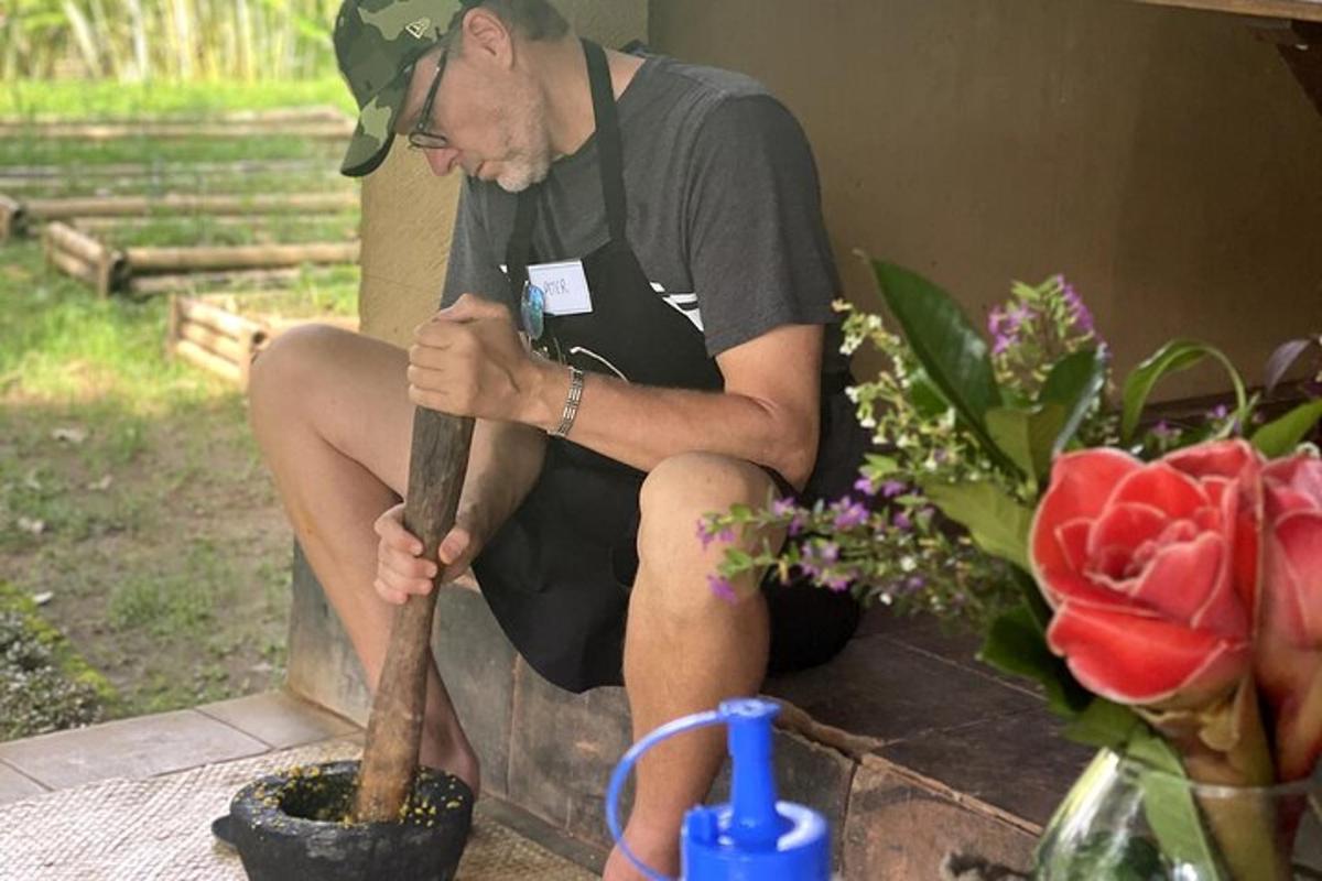 isang lalaking naka-apron na nakaupo sa isang bato na may hawak na patpat