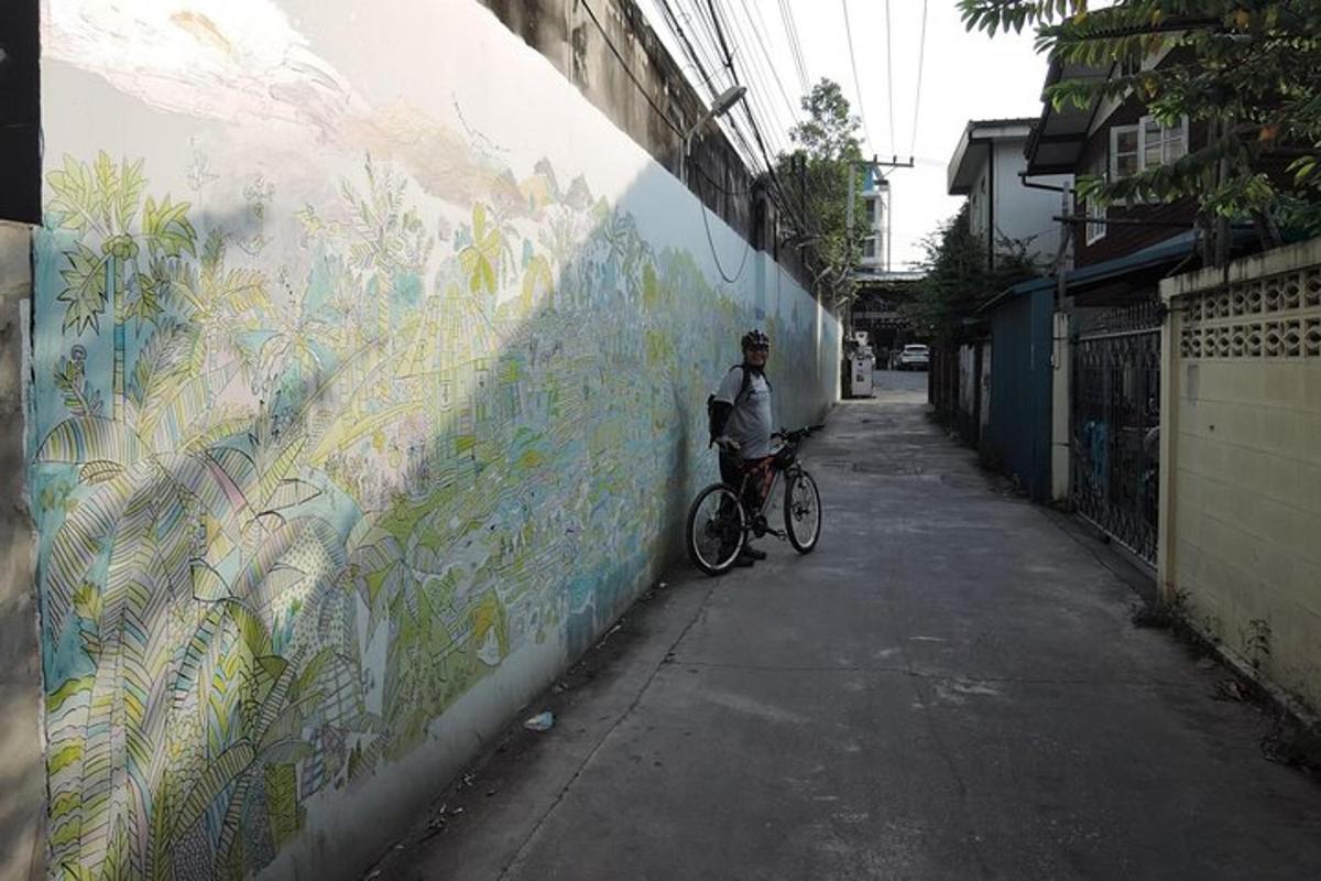 um homem andando de bicicleta em frente a um muro