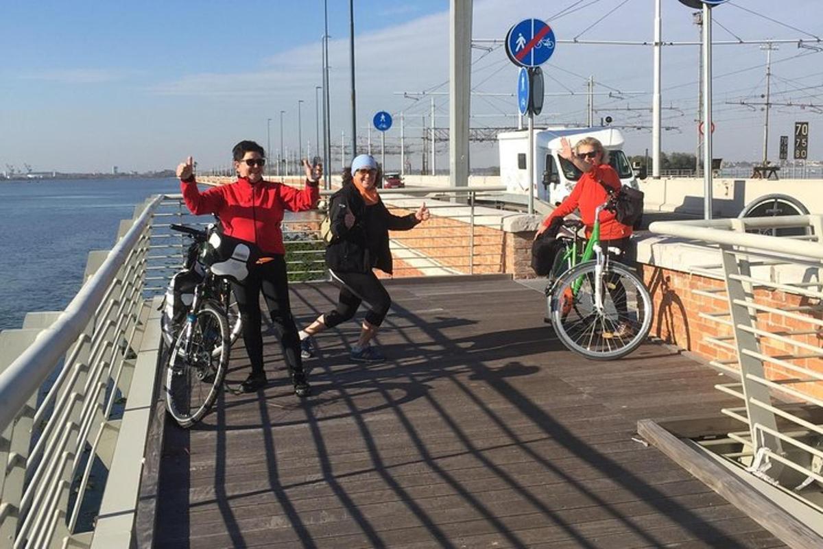 tres persones anant en bicicleta per un passeig marítim a prop de l'aigua