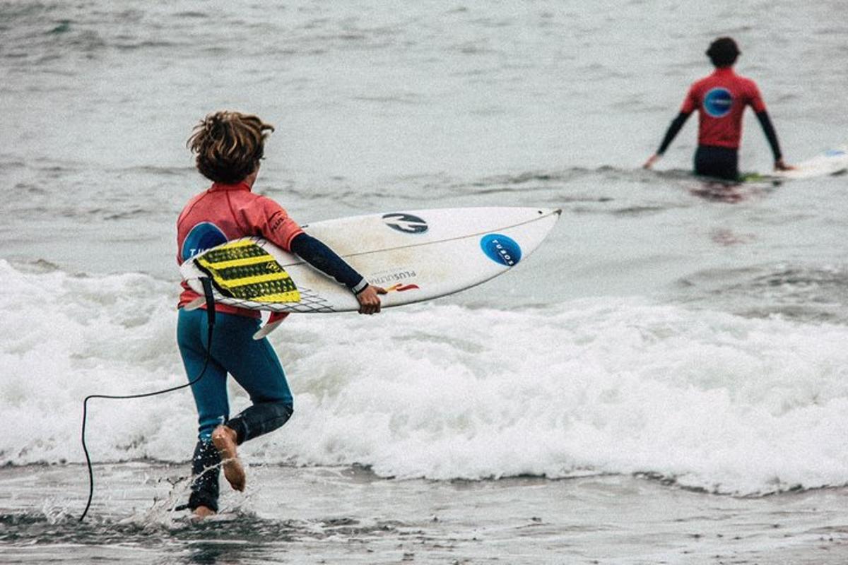 zwei Menschen, die mit einem Surfbrett ins Meer gehen