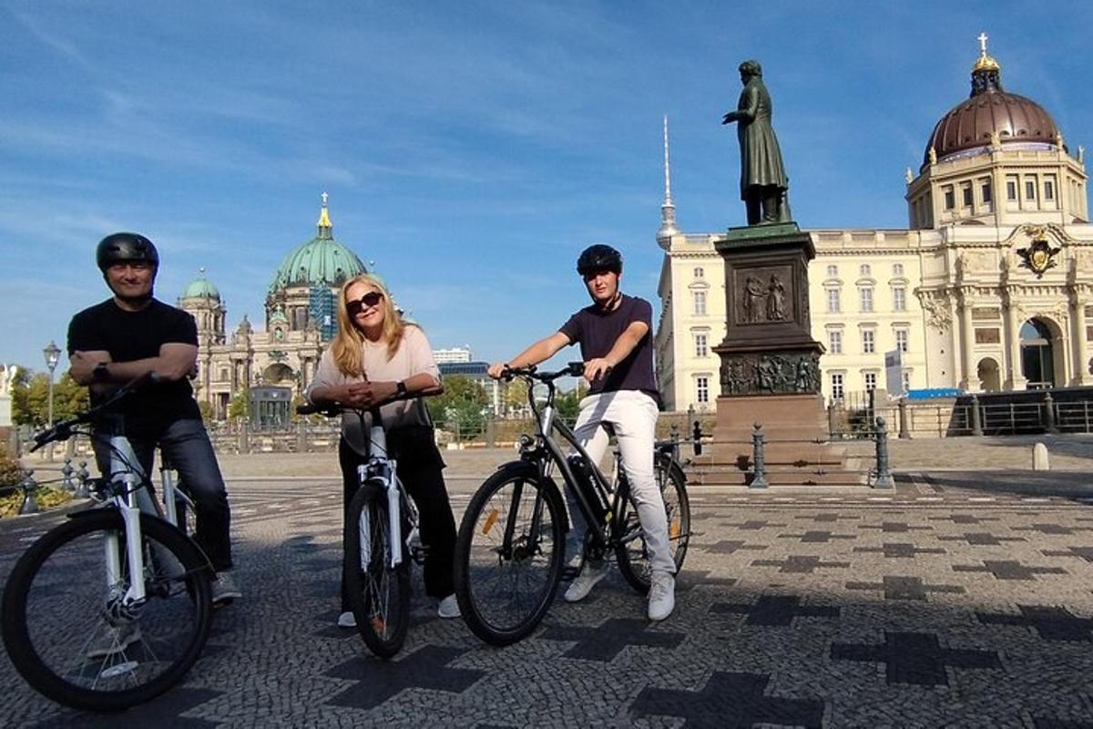 tři lidé jedoucí na kolech před budovou