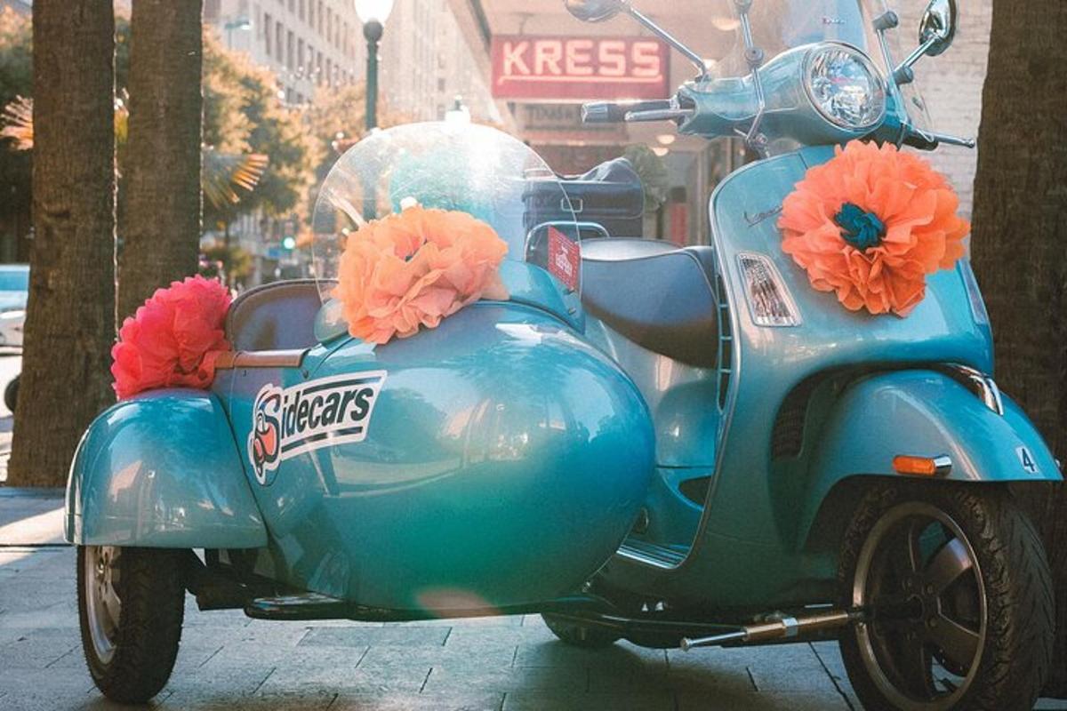 un escúter blau aparcat en un carrer amb flors