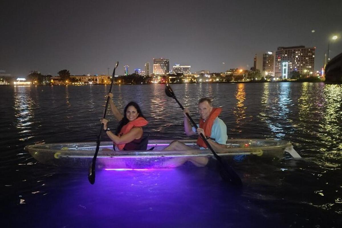 a man and woman kayaking on the water at night