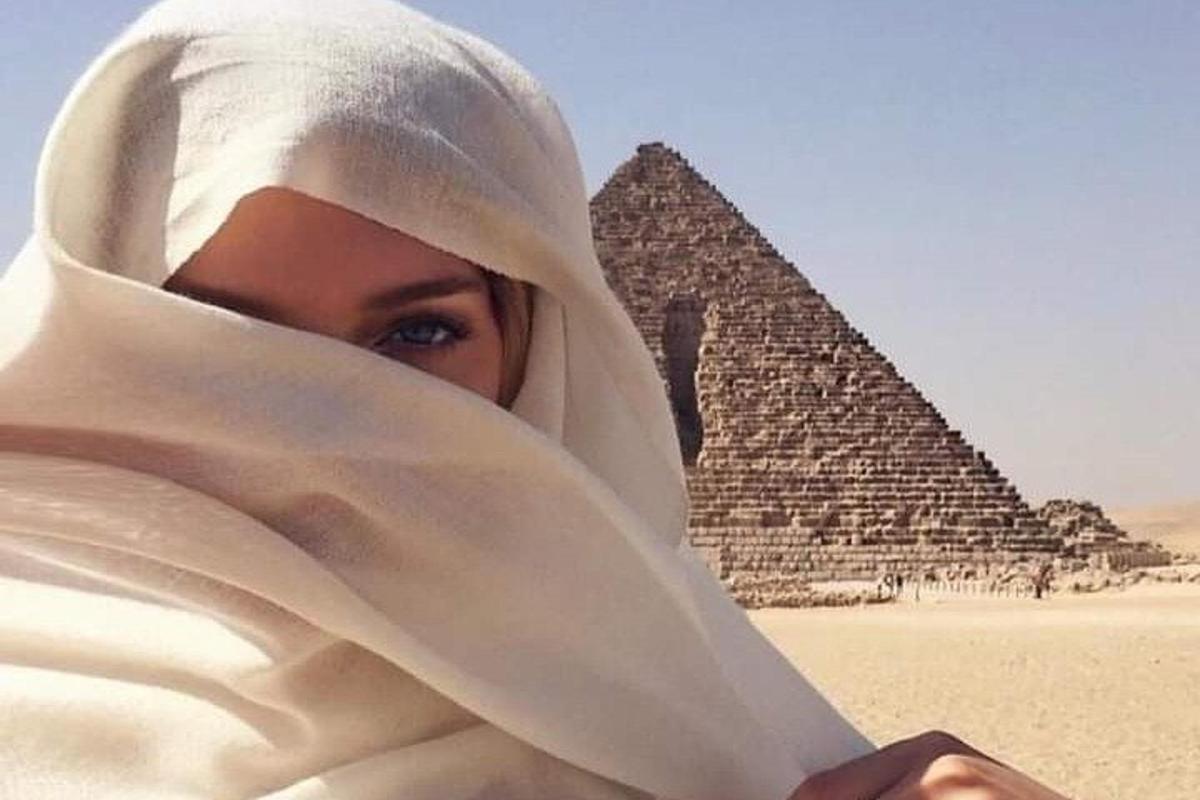 una donna che indossa l'hijab in piedi davanti alle piramidi