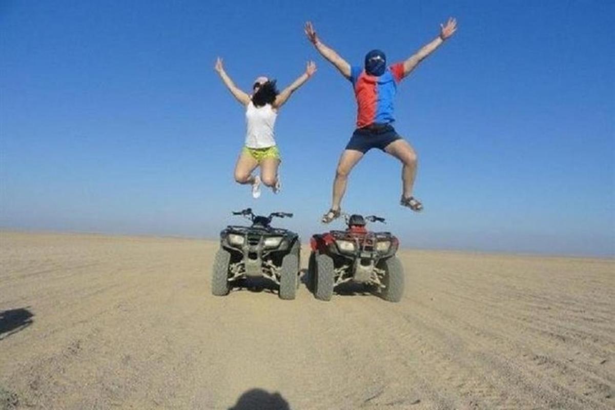 Două persoane sărind în aer lângă un ATV în deșert