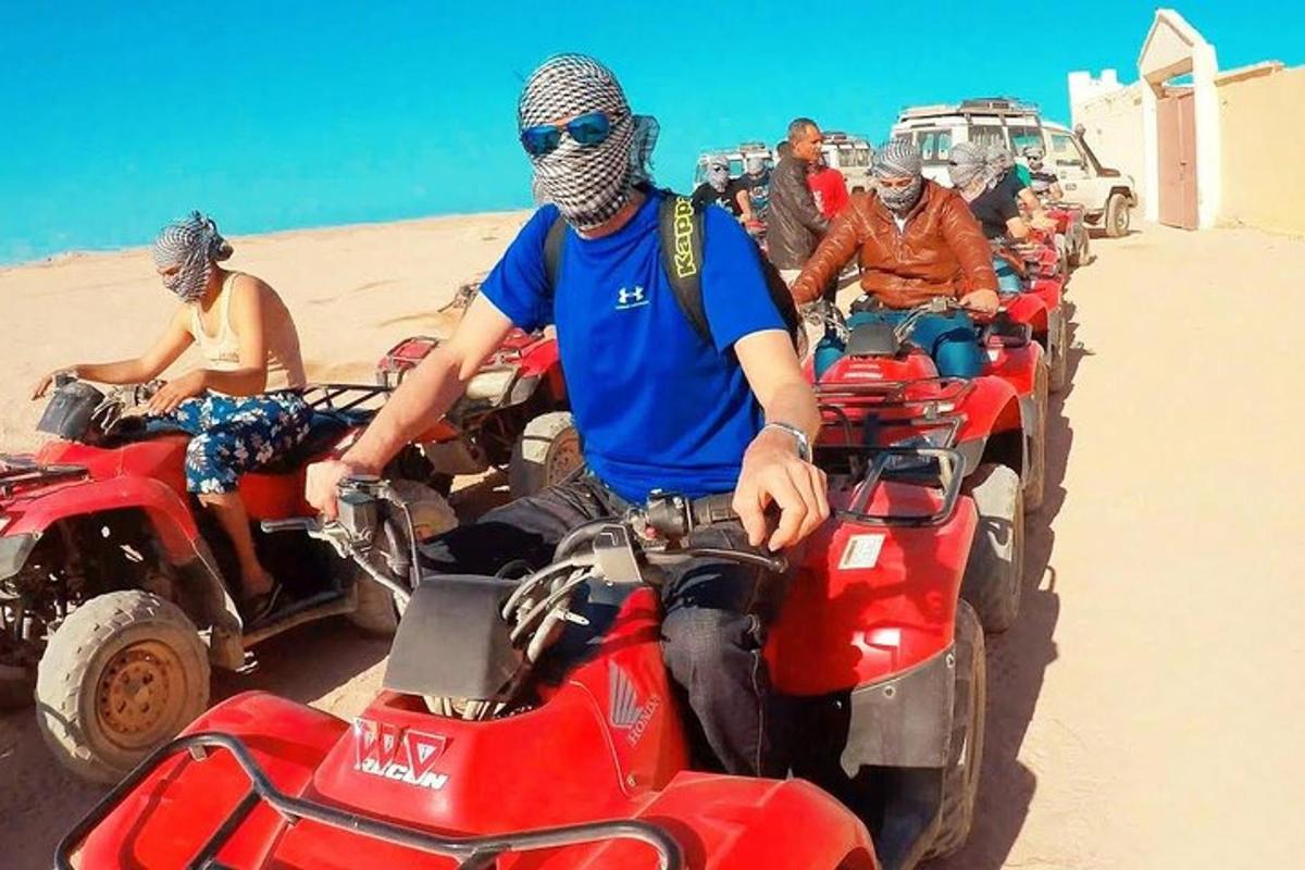 un grup de oameni care călătoresc cu ATV-uri pe nisip