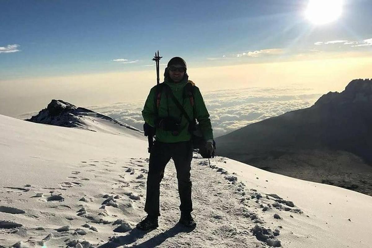 moški, ki stoji na vrhu zasnežene gore