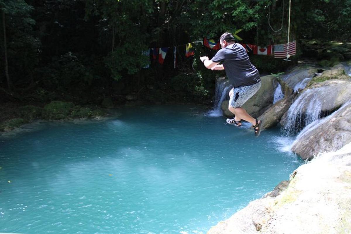 a man jumping off a rock into a pool of water