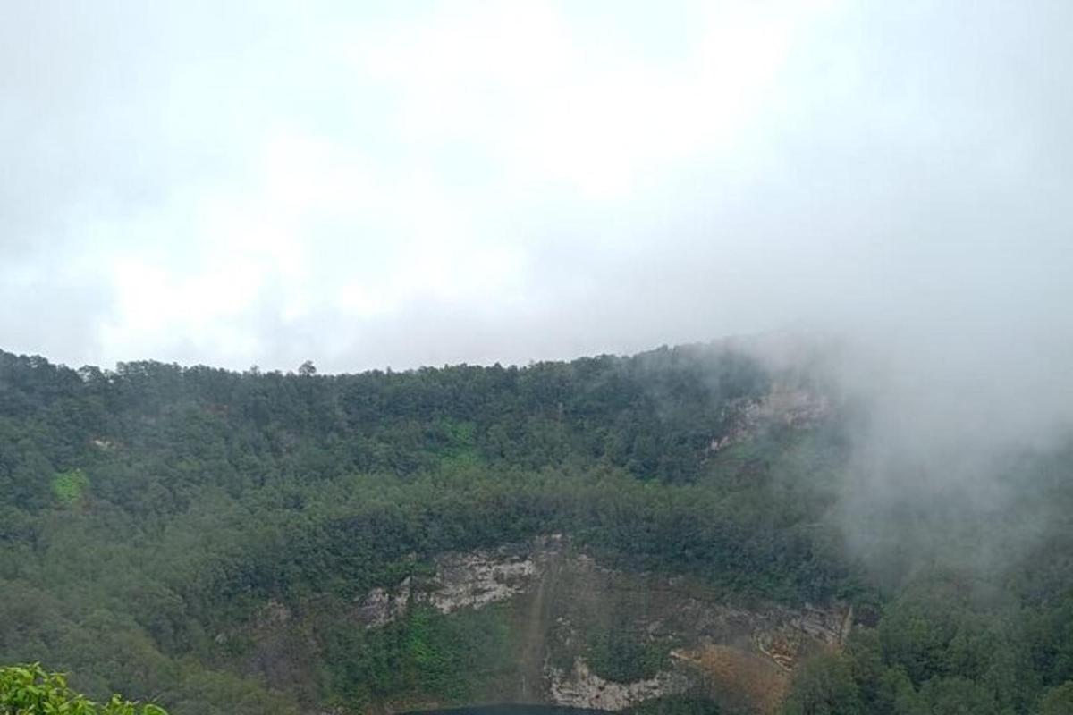 a view of a mountain with trees and clouds