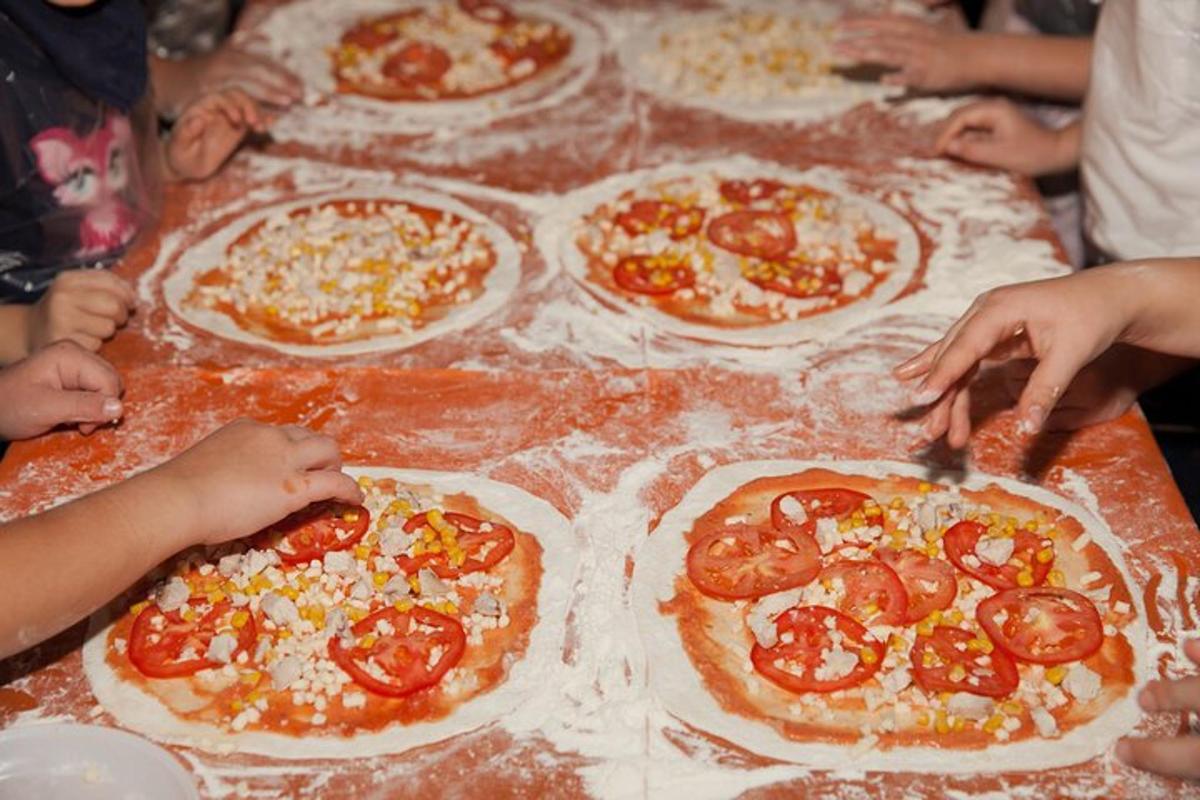 skupina lidí pečoucích pizzy na stole