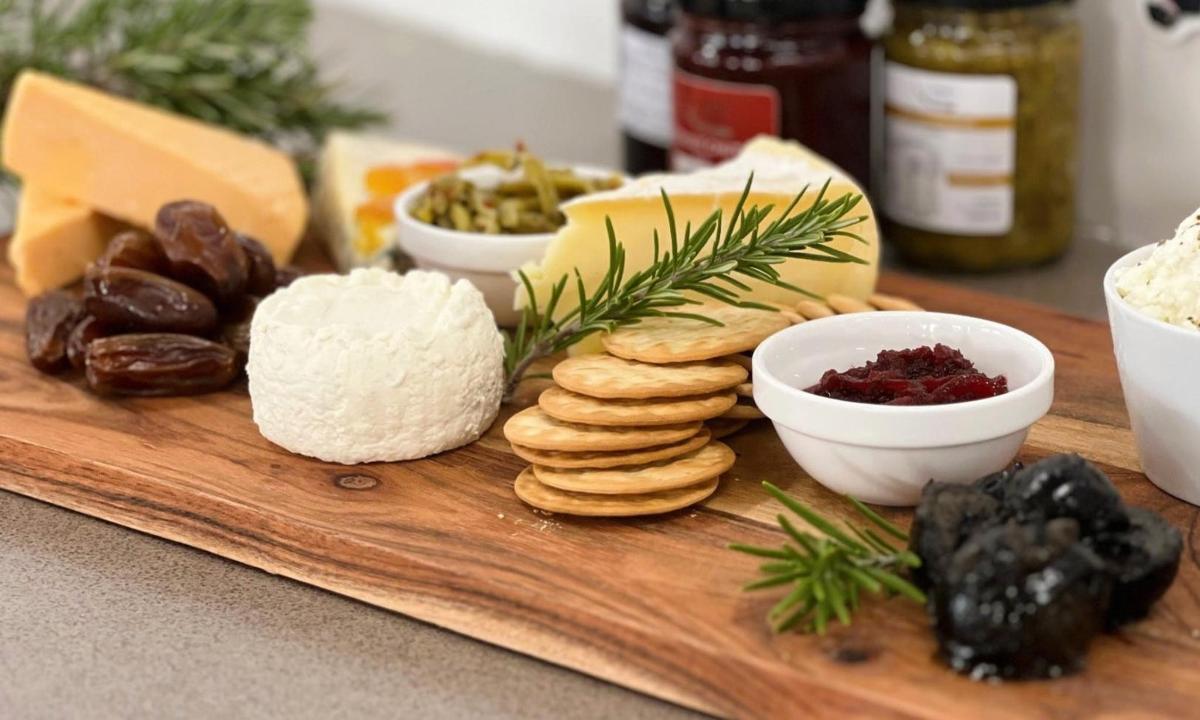 Una tabla de cortar de madera con queso y otros ingredientes.