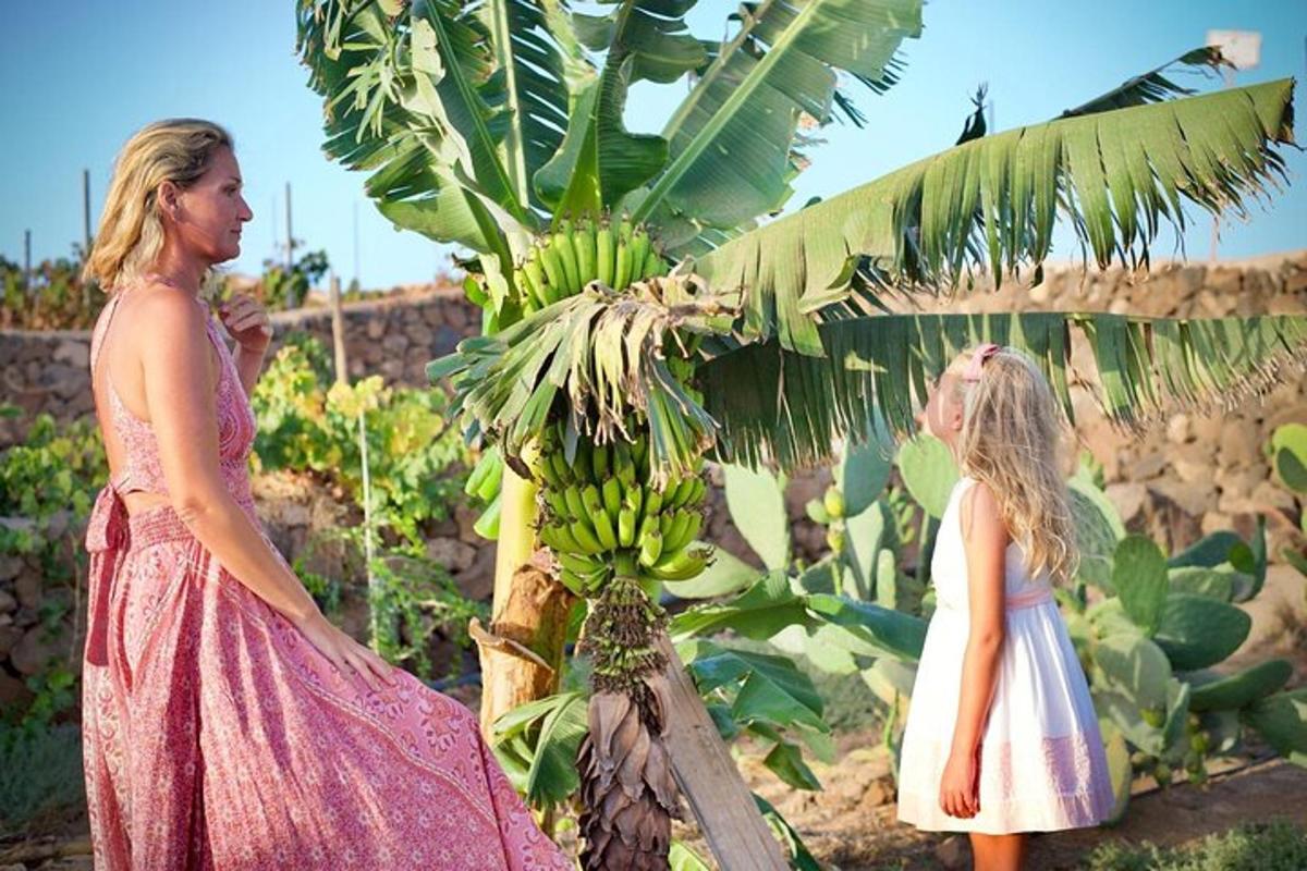 Kona og lítil stúlka standa við hlið bananatrés