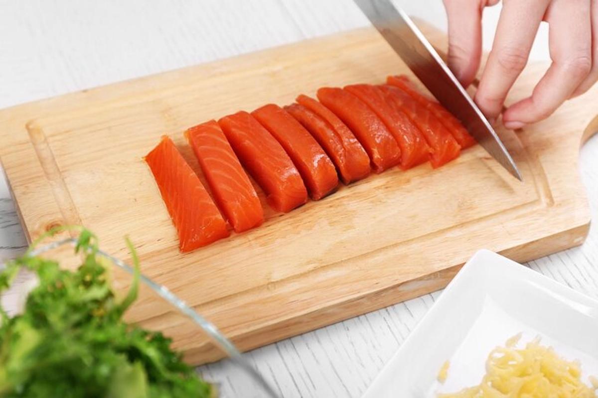 osoba krájející mrkev na prkénku nožem