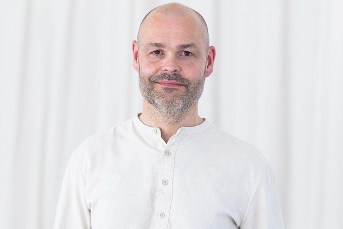 un uomo in camicia bianca che posa per una foto