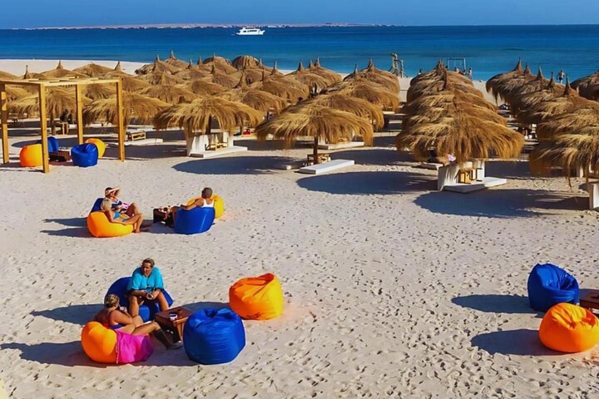 um grupo de pessoas sentadas em uma praia com guarda-sóis de palha