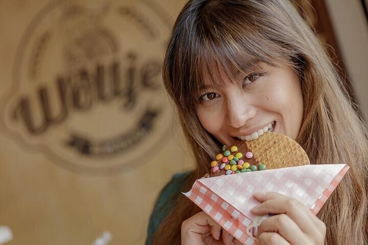 seorang gadis muda makan biskut dan memegang kon