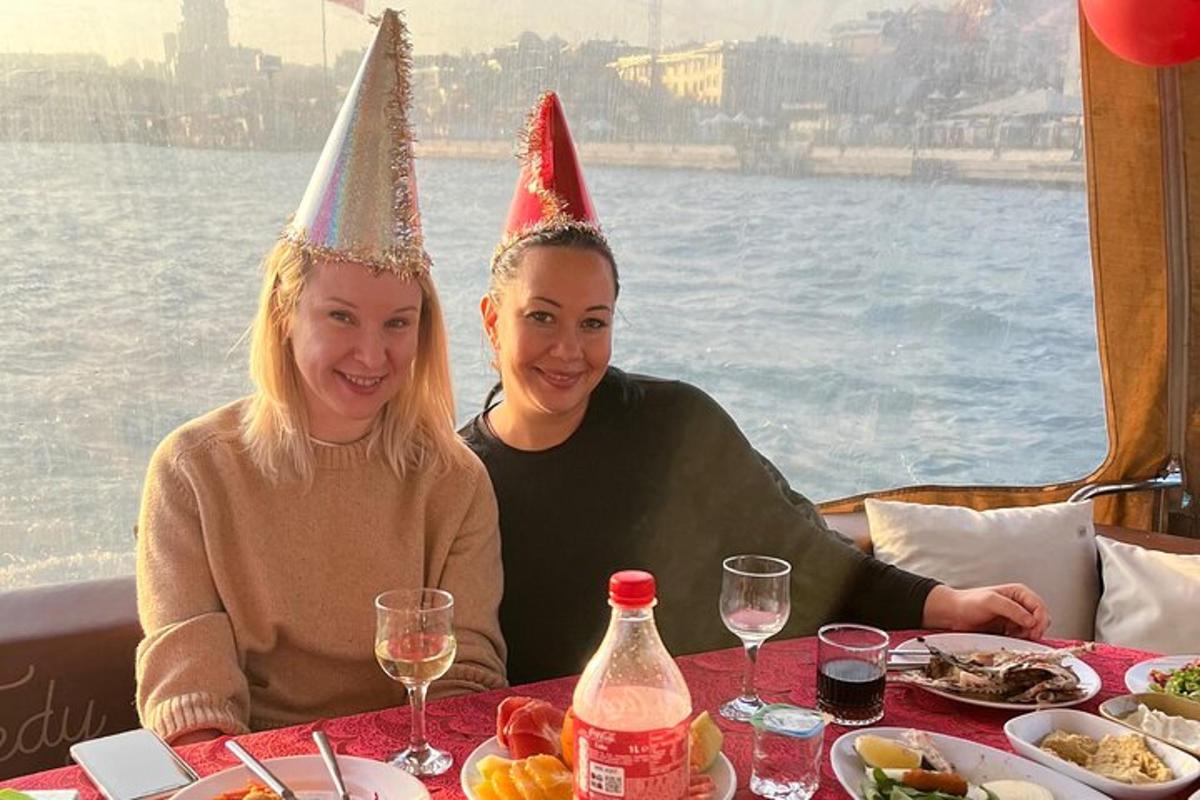 dve ženy sediace pri stole v párty klobúkoch