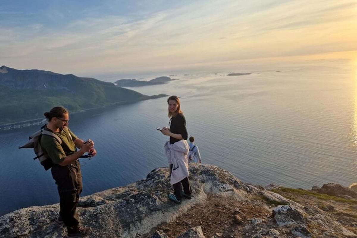duas pessoas em pé no topo de uma montanha com vista para a água