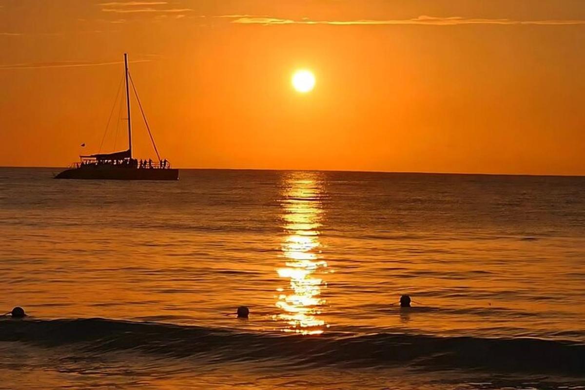 Un barco en el océano al atardecer con gente en el agua.