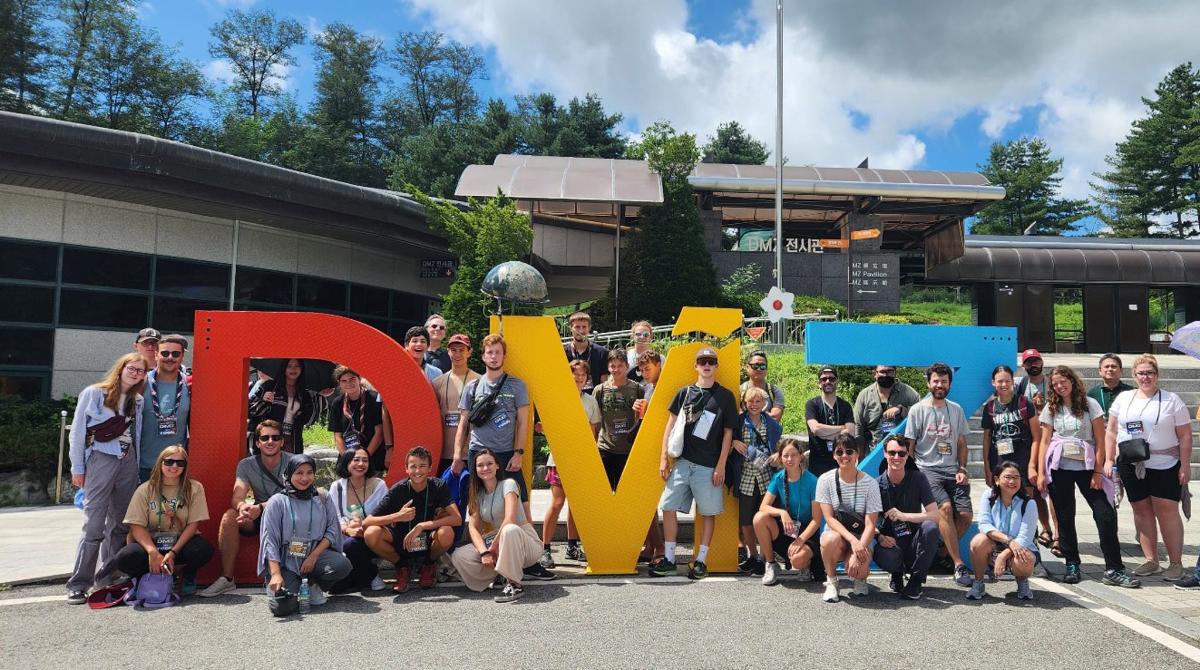 a group of people posing in front of a large sign