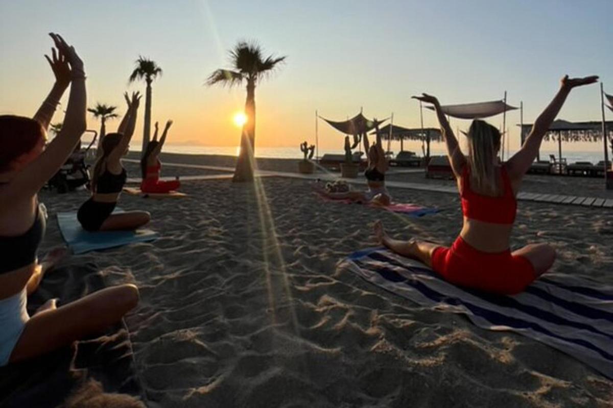 a group of people sitting on the beach watching the sunset