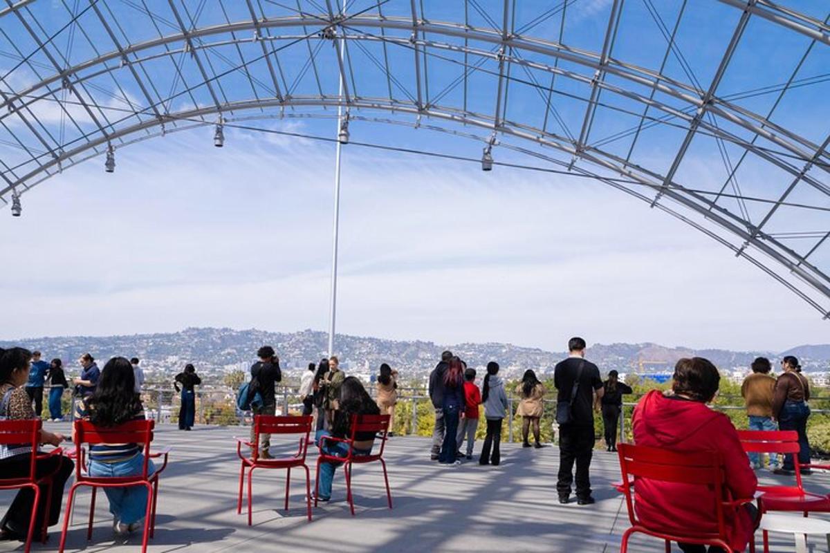 a group of people sitting in red chairs under a glass roof